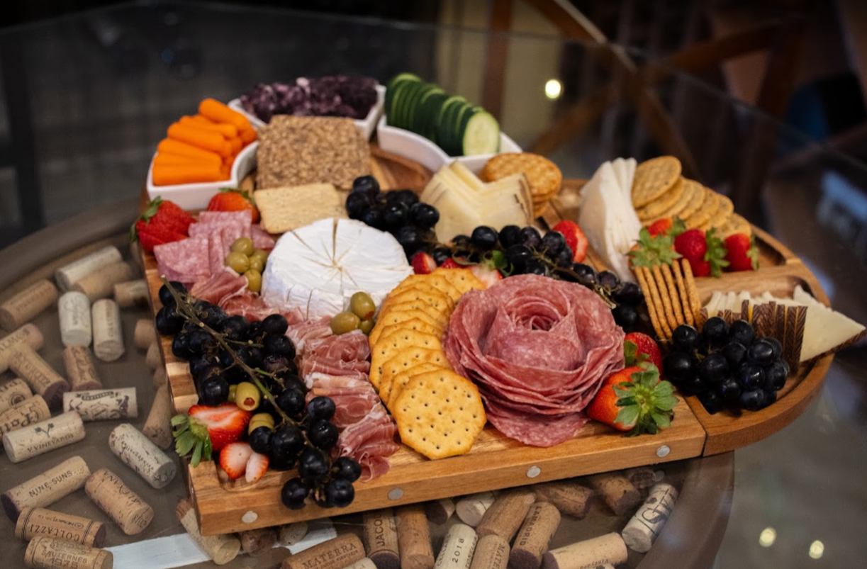 Heart-shaped charcuterie board with a salami rose, fruits, veggies, and cheese